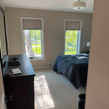 Bedroom with two windows, new carpet, neutral paint and painted trim