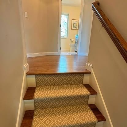 Wood staircase with a patterned stair runner, white risers and painted trim